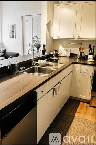 A kitchen with white cabinets and a wooden counter top.
