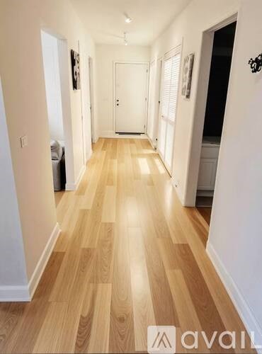 A long hallway with wood flooring and white walls.
