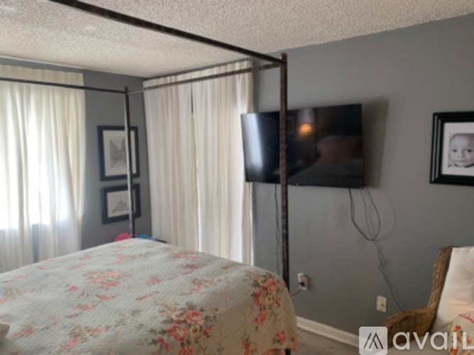 A bedroom with a four poster bed and a television on the wall.