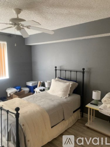 A bedroom with a bed, nightstand, and window.