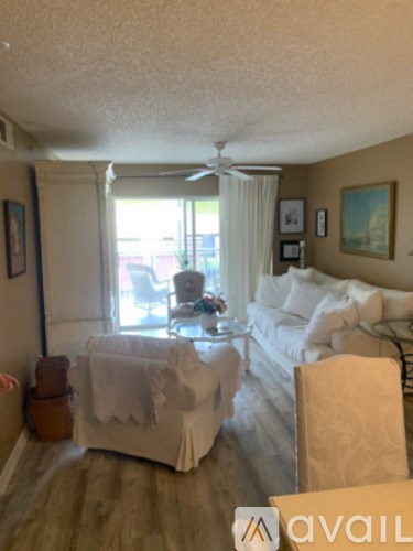 A living room with a white couch and a fan on the ceiling.