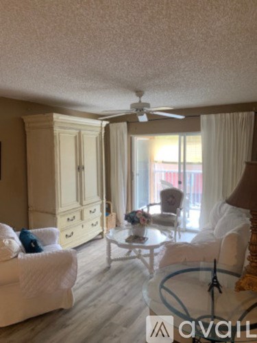 A living room with a white couch, a white chair, a white coffee table, and a white cabinet.