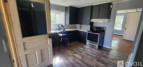 A kitchen with black cabinets and a wooden floor.