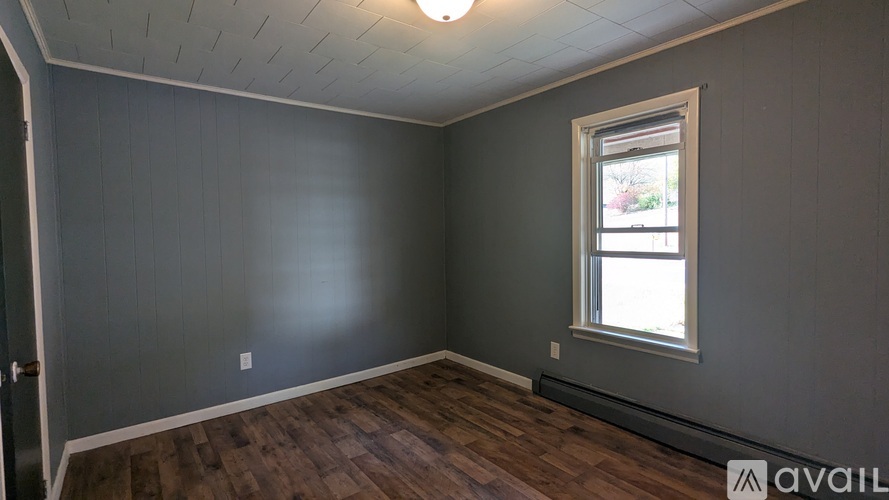 A room with a window and wooden floors.