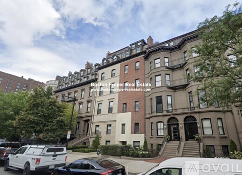 A row of brown and beige townhouses with cars parked in front.