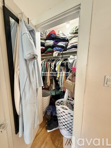 A small closet with clothes and a basket.