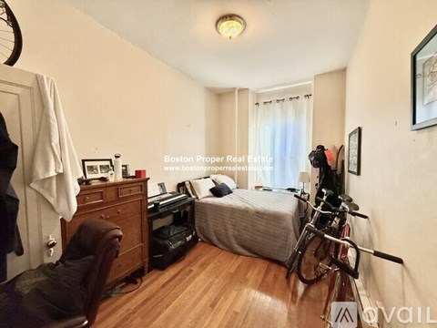 A bedroom with a bed, a desk, and a bicycle.