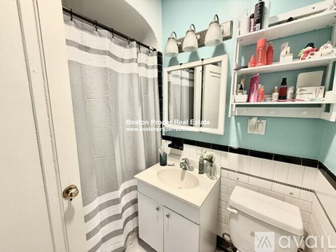 A bathroom with a white sink and toilet, a striped shower curtain, and a mirror above the sink.