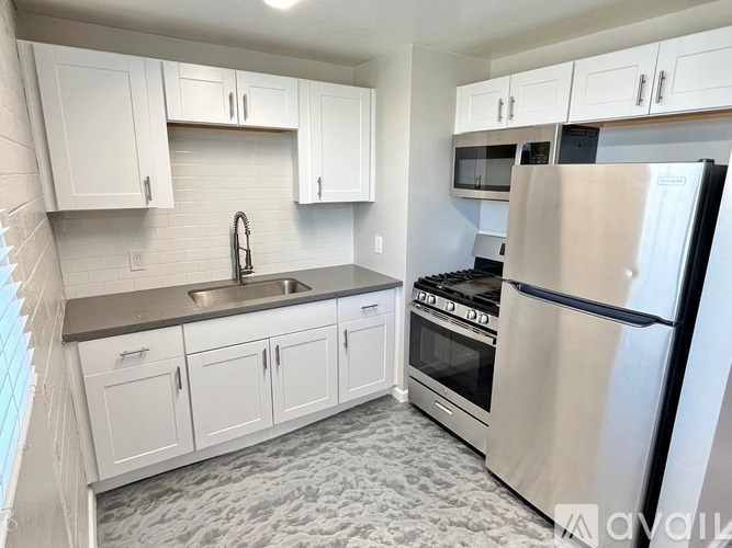 A kitchen with white cabinets and a stainless steel refrigerator.