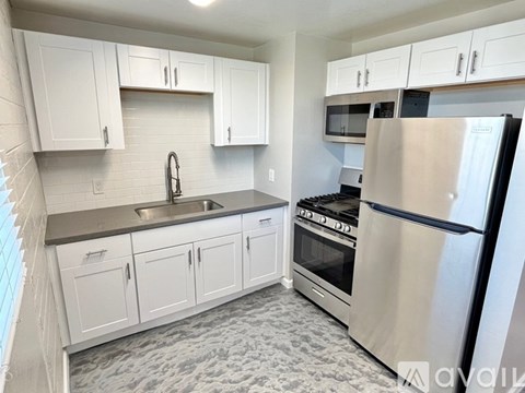 A kitchen with white cabinets and a stainless steel refrigerator.