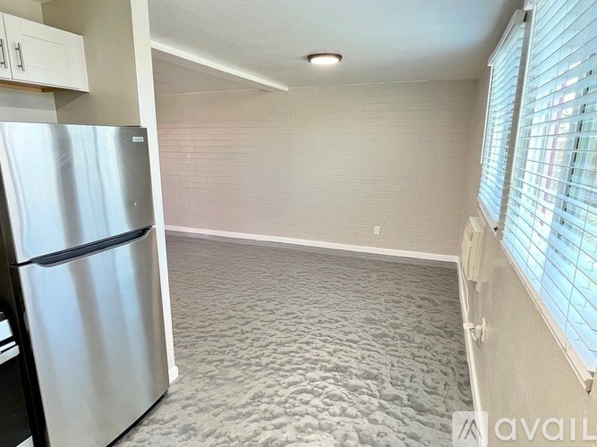 A kitchen with a refrigerator and a carpeted floor.