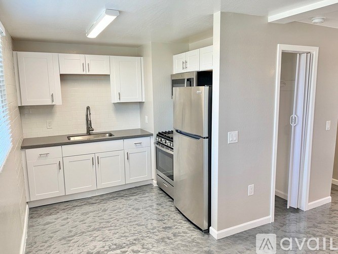 A kitchen with white cabinets and a stainless steel refrigerator.