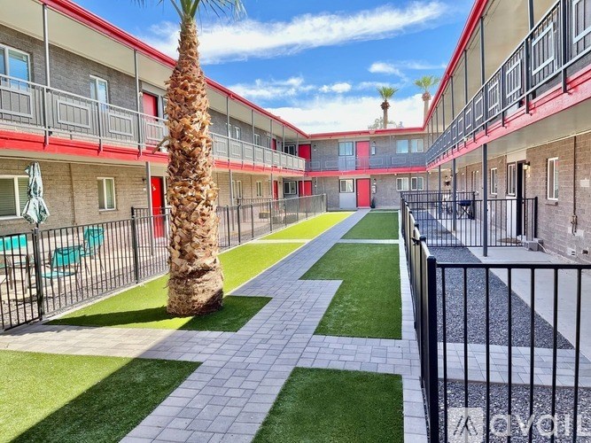 A palm tree stands in a courtyard between two buildings.