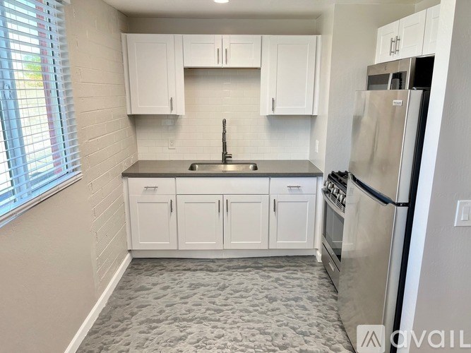 A kitchen with white cabinets and a stainless steel refrigerator.