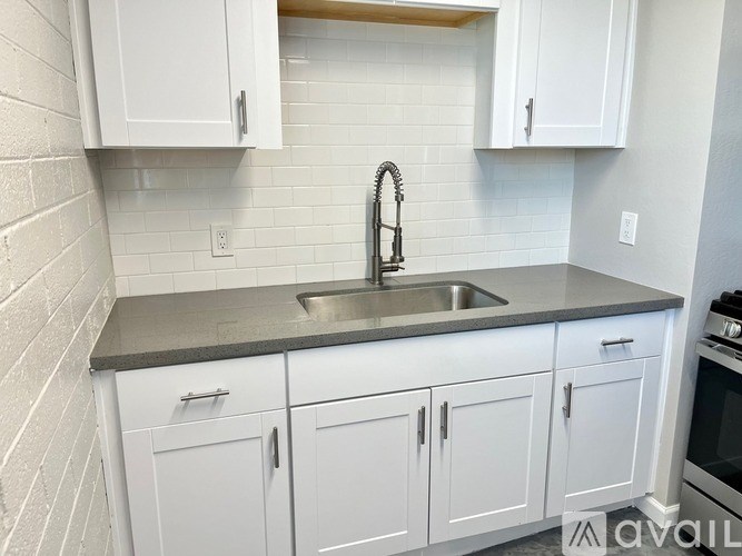 A kitchen with white cabinets and a grey countertop.