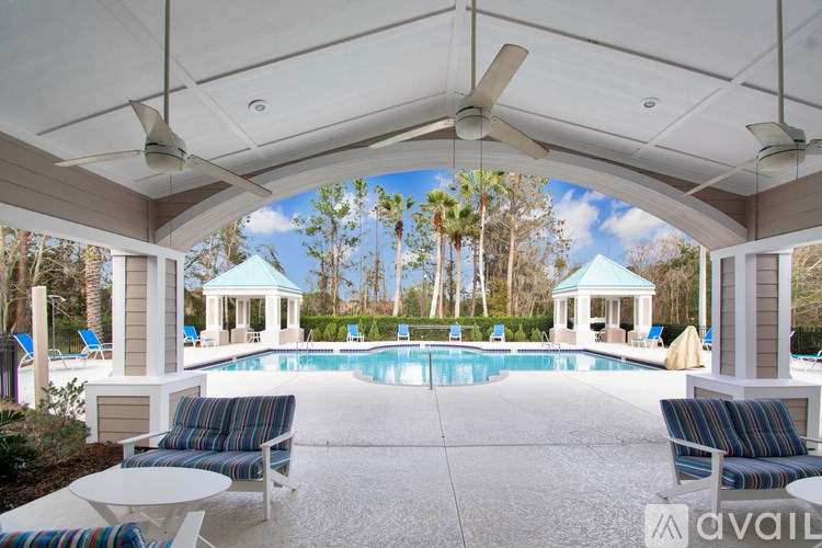 A pool area with a white canopy and blue and white striped chairs.