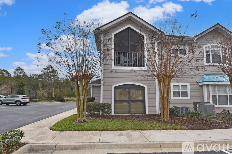 A grey house with a balcony and a tree in front.