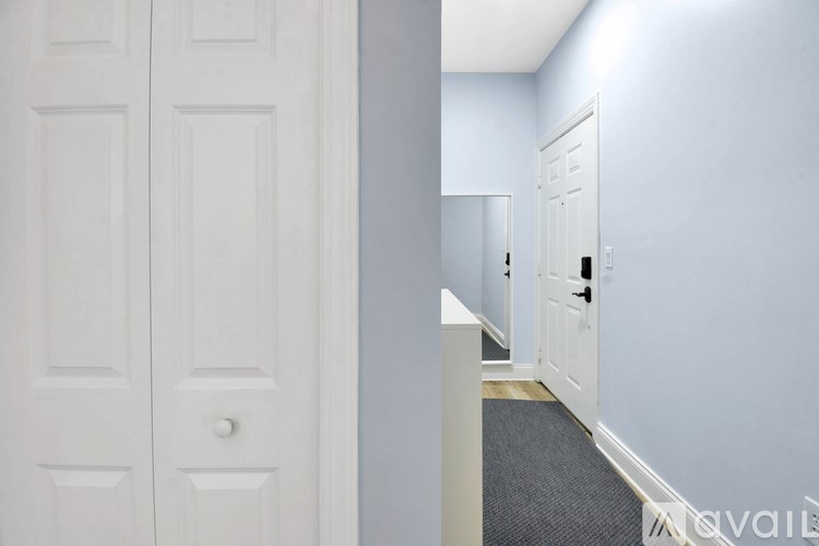 A hallway with a white door on the left and a white door on the right.