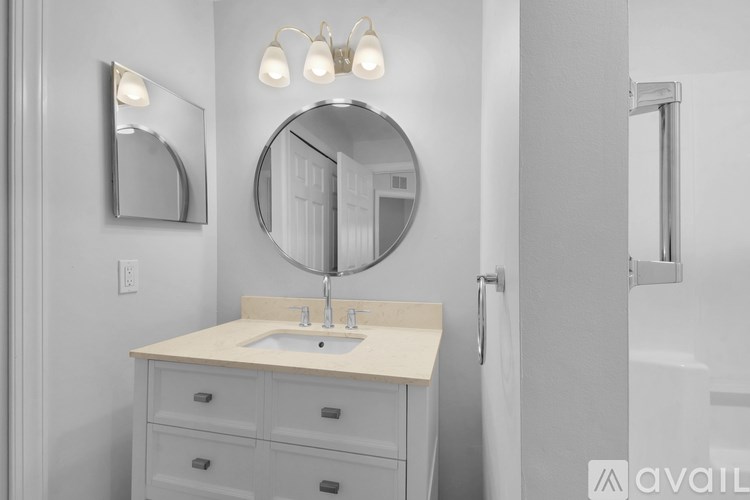 A bathroom with a sink, mirror, and light fixture.