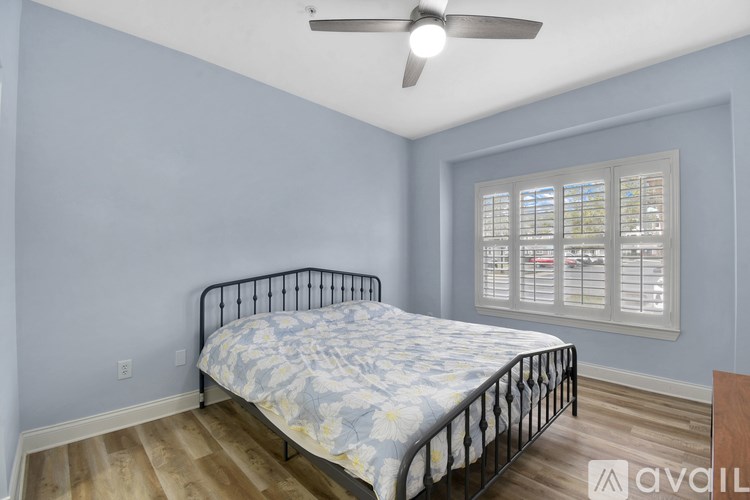 A bedroom with a bed, a ceiling fan, and a window with blinds.