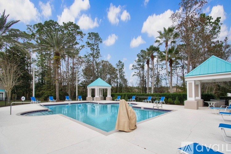 A pool surrounded by trees and chairs.