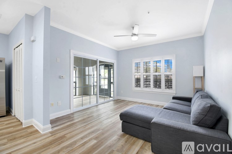 A living room with a grey couch and a ceiling fan.