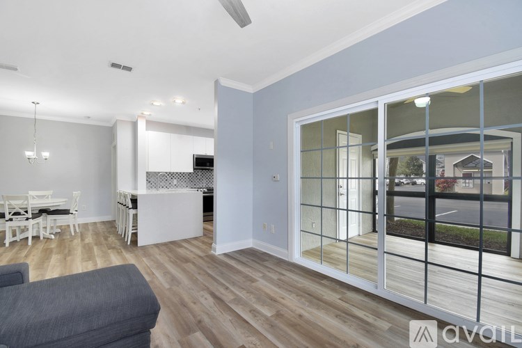 A modern living room with a grey sofa and a dining area with a table and chairs.