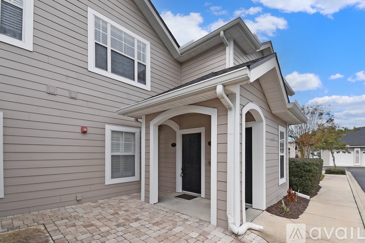 A house with a grey siding and a black door is available for rent.