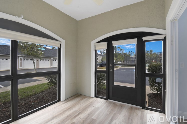 A room with a view of a street through a glass door.