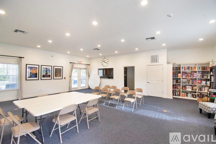 A room with a white table and chairs, a bookshelf, and a clock on the wall.