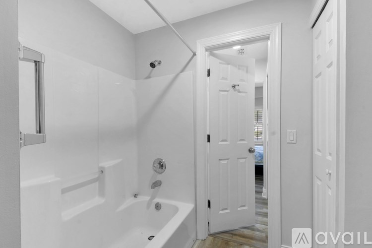 A white bathroom with a tub and a door.