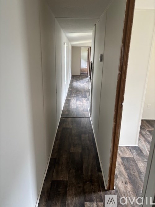 A long hallway with wood floors and white walls.