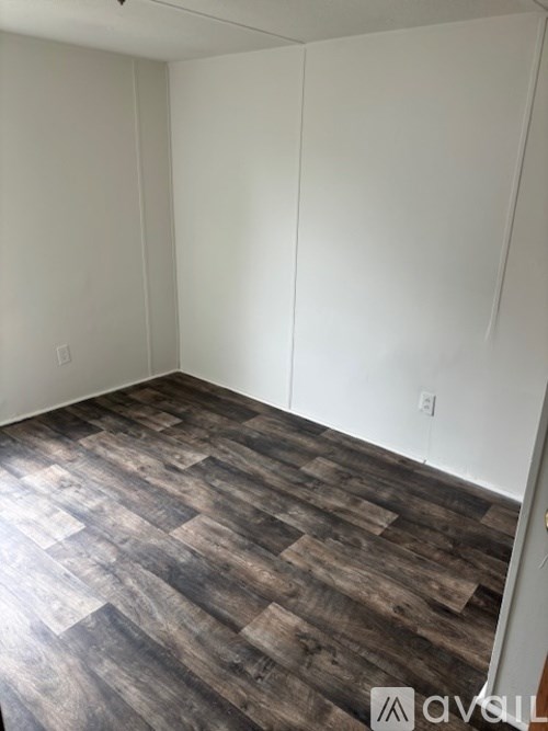 A room with wooden flooring and white walls.