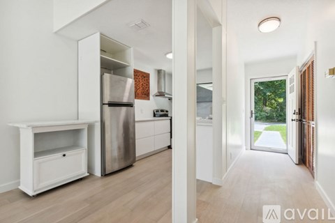 A modern kitchen with white cabinets and a wooden floor.