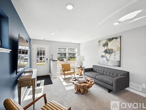 A living room with a grey couch, a coffee table, and a painting on the wall.