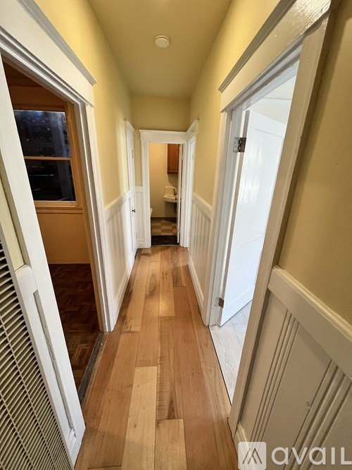 A long hallway with wood floors and white walls.