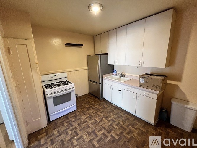 A kitchen with a white stove, refrigerator, and cabinets.
