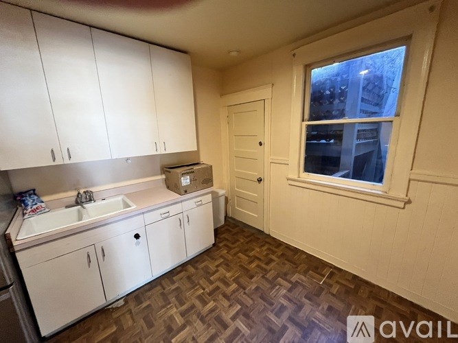 A kitchen with white cabinets and a window.