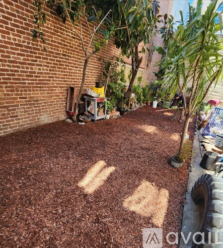 A backyard with a brown mulch ground cover and a brick wall.