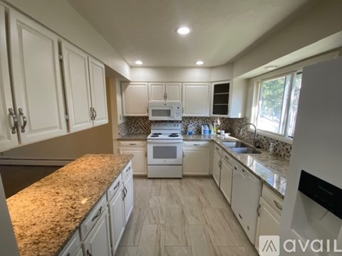 A kitchen with white cabinets and a granite countertop.