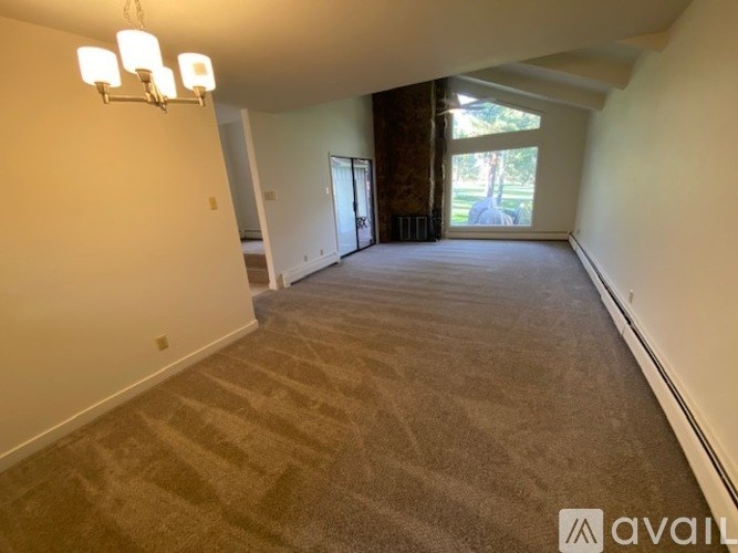 A spacious room with a carpeted floor and a large window.