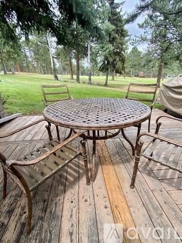 A round table with four chairs is set on a wooden deck.
