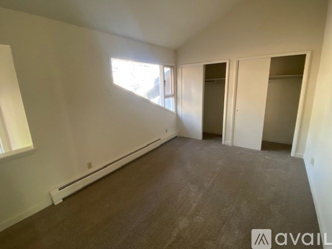 A room with a carpeted floor and a window letting in sunlight.