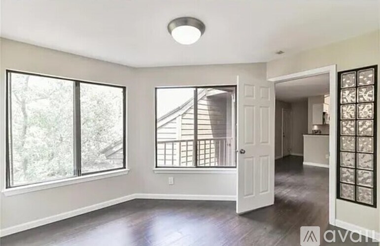 A room with a large window and a door leading to another room.