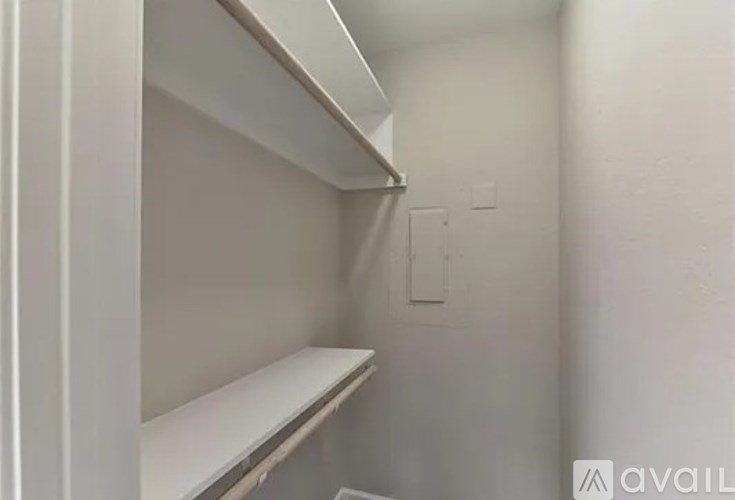 A small, empty white closet with a shelf and a light switch.