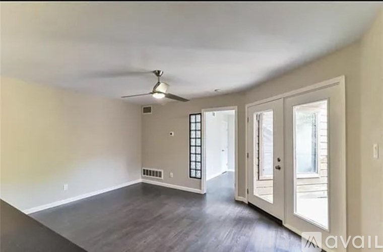 A spacious room with a ceiling fan and sliding glass doors.