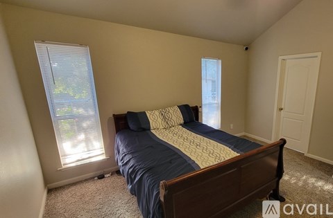 A bedroom with a bed, carpet, and a window.