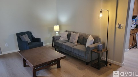 A living room with a grey couch, a blue chair, and a wooden coffee table.