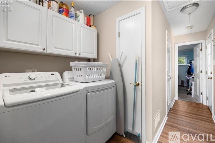 A laundry room with a washer and dryer and a broom in the doorway.