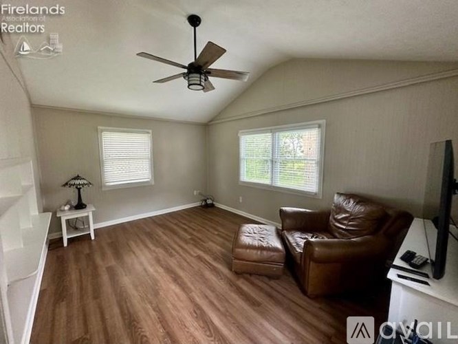 A living room with a brown leather couch and a ceiling fan.